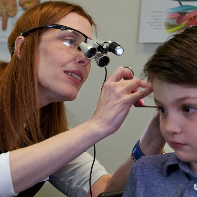 A photo of an audiologist checking a child's ear