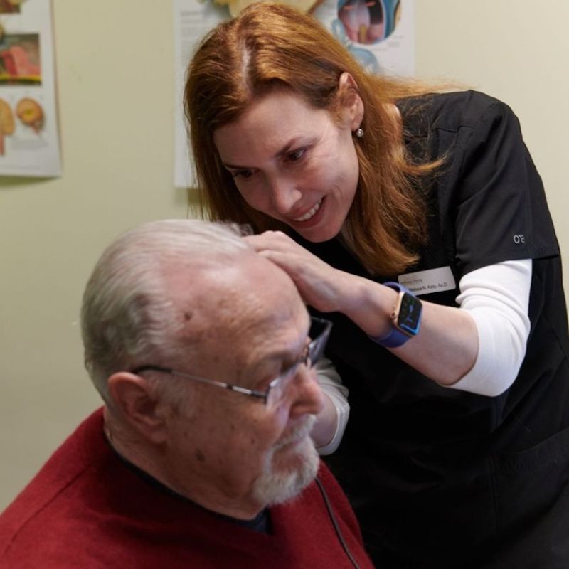 A photo of an audiologist checking a man's ear